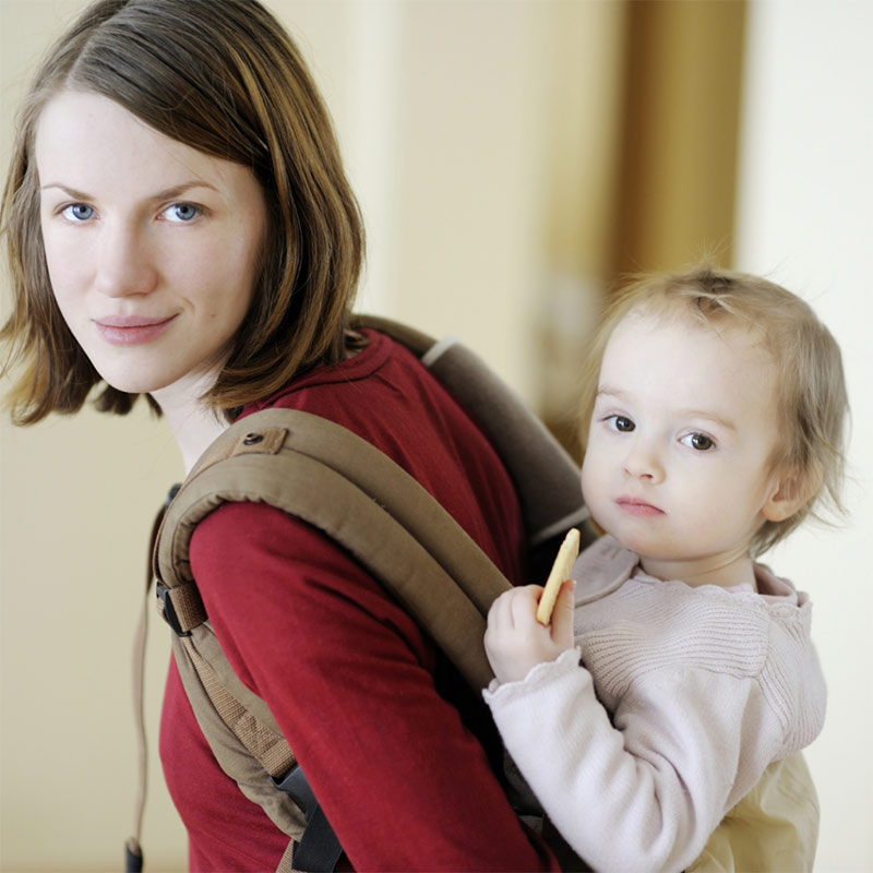 Woman holding child in a backpack carrier